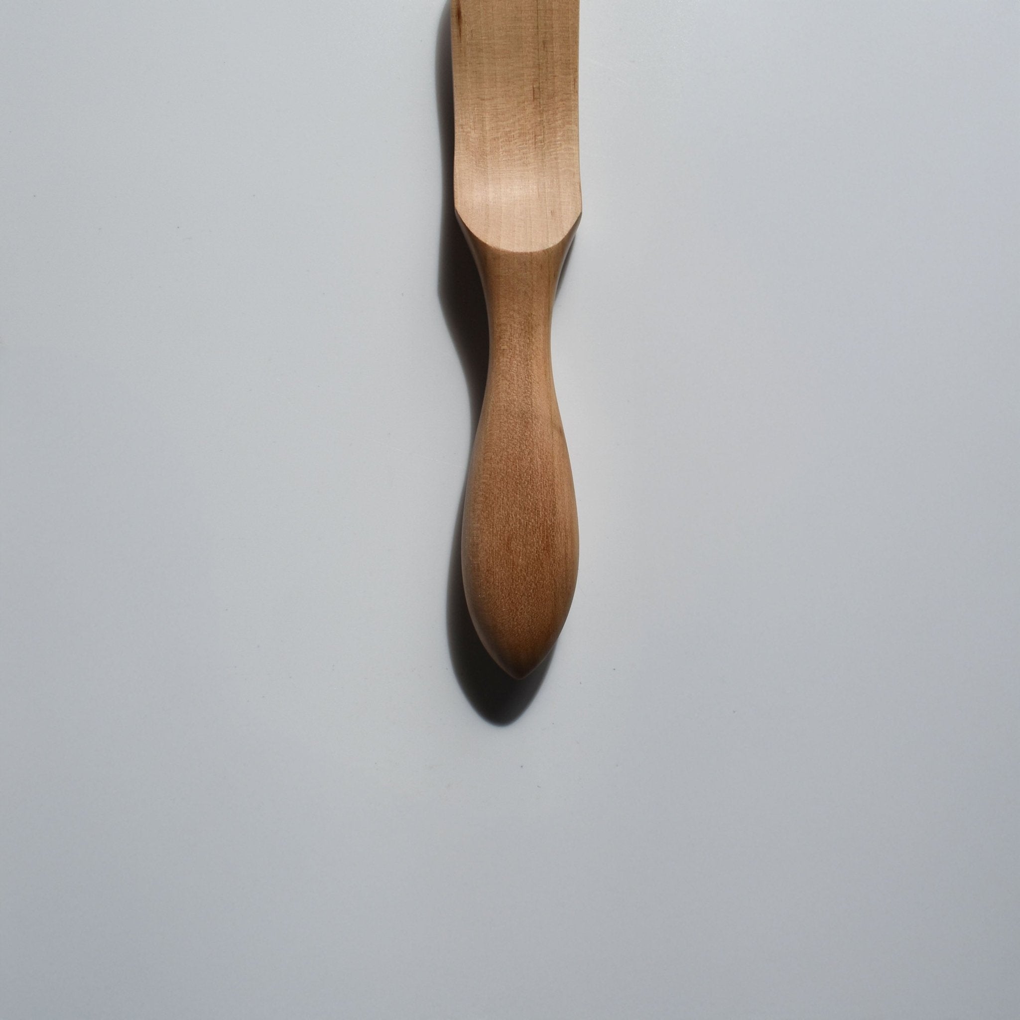 Close-up of the Sakura wood butter knife showing the smooth carved handle and natural wood grain