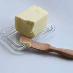 Sakura wood butter knife spreading butter from a glass butter dish
