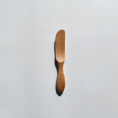 Sakura wood butter knife with smooth carved handle and natural wood grain on a white background