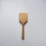 Sakura wood flat spatula with wide paddle shape, hanging hole, and natural wood grain on a white background