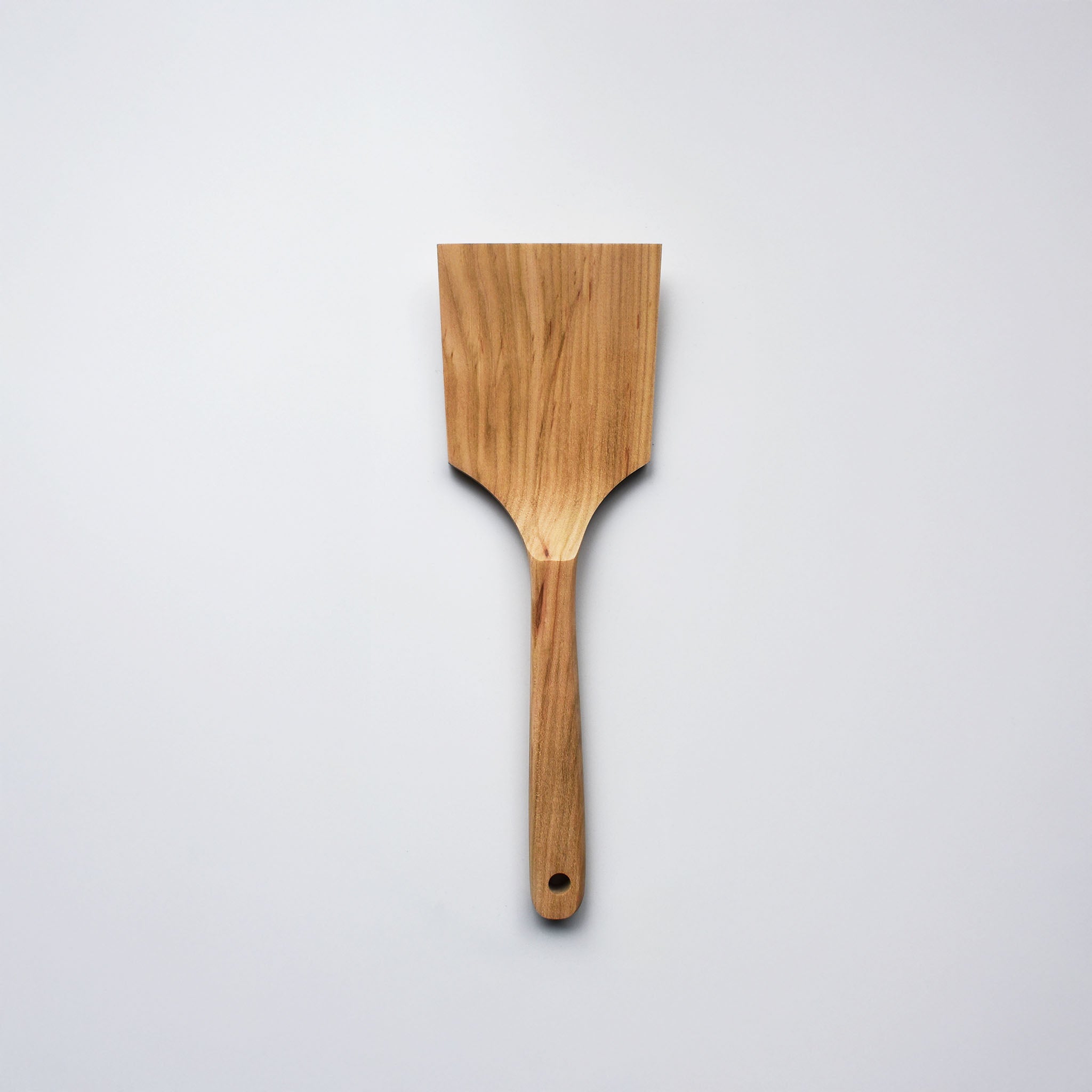 Sakura wood flat spatula with wide paddle shape and natural wood grain on a white background