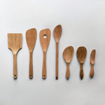 Sakura wood Japanese kitchen utensil set with spatulas, spoons, and cooking tools arranged on a white background