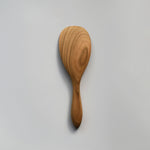 Close-up of the Sakura wood round rice paddle showing the smooth carved surface and natural wood grain