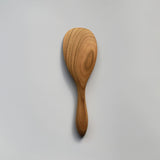 Close-up of the Sakura wood round rice paddle showing the smooth carved surface and natural wood grain