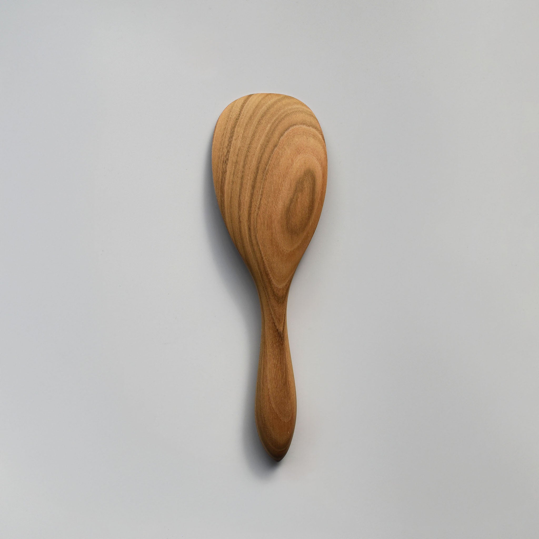 Close-up of the Sakura wood round rice paddle showing the smooth carved surface and natural wood grain