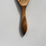 Close-up of the Sakura wood round rice paddle showing the carved handle and natural wood grain