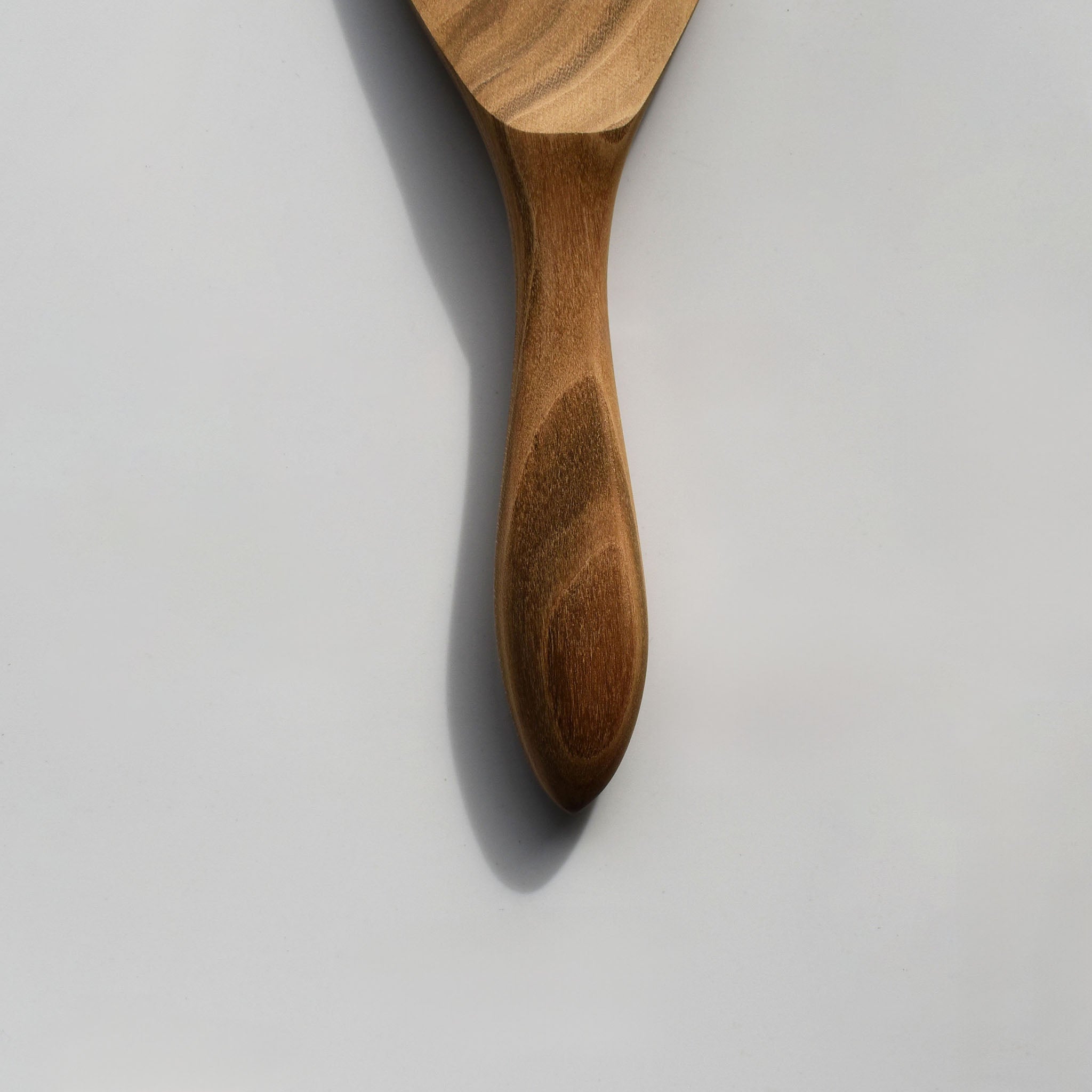 Close-up of the Sakura wood round rice paddle showing the carved handle and natural wood grain