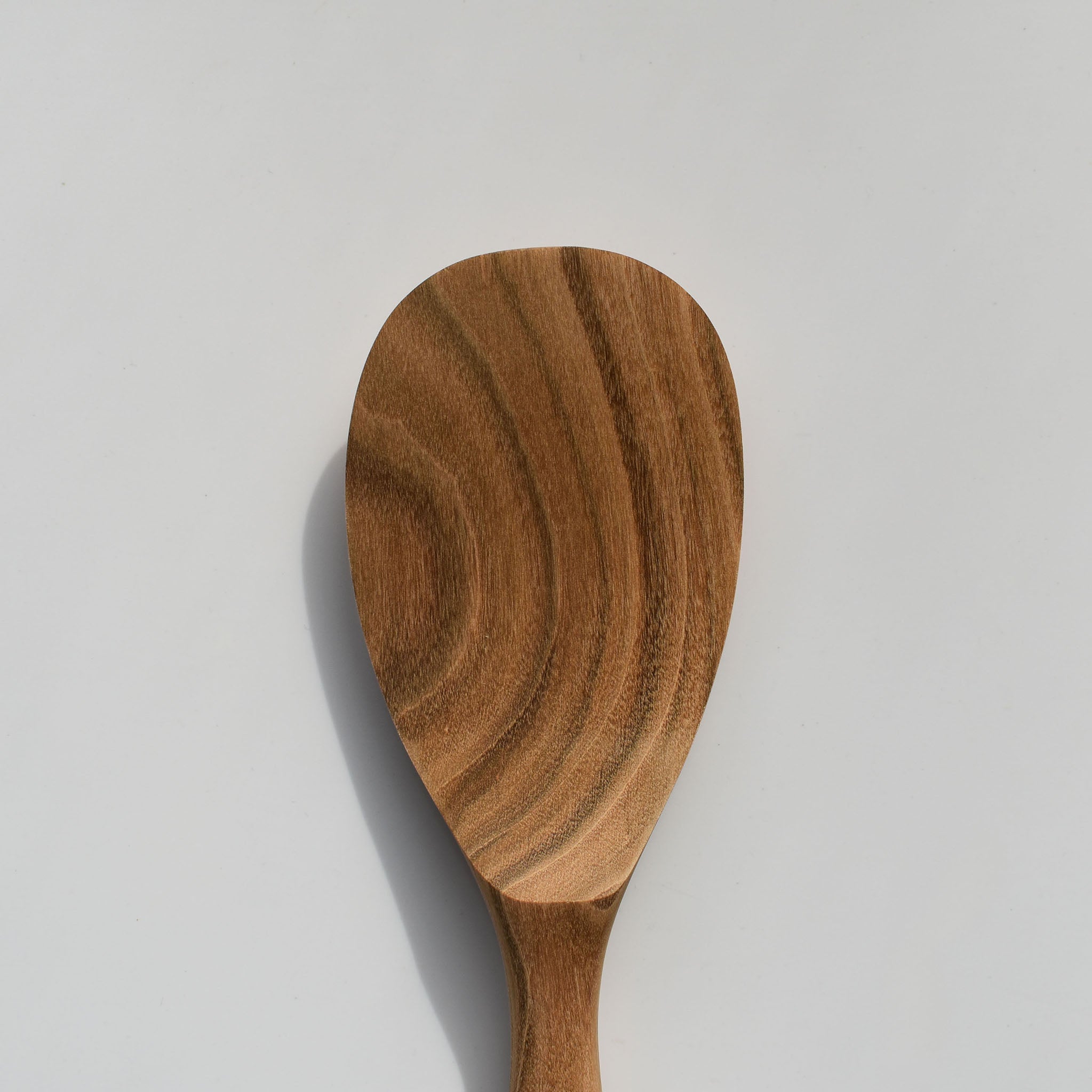 Close-up of the Sakura wood round rice paddle showing the carved paddle head and natural wood grain