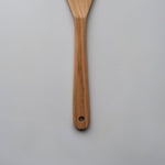 Close-up of the Sakura wood slotted spatula showing the carved handle, hanging hole, and natural wood grain