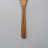 Close-up of the Sakura wood slotted spatula showing the carved handle, hanging hole, and natural wood grain