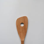 Close-up of the Sakura wood slotted spatula showing the round slot and natural wood grain