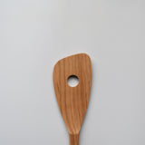 Close-up of the Sakura wood slotted spatula showing the round slot and natural wood grain