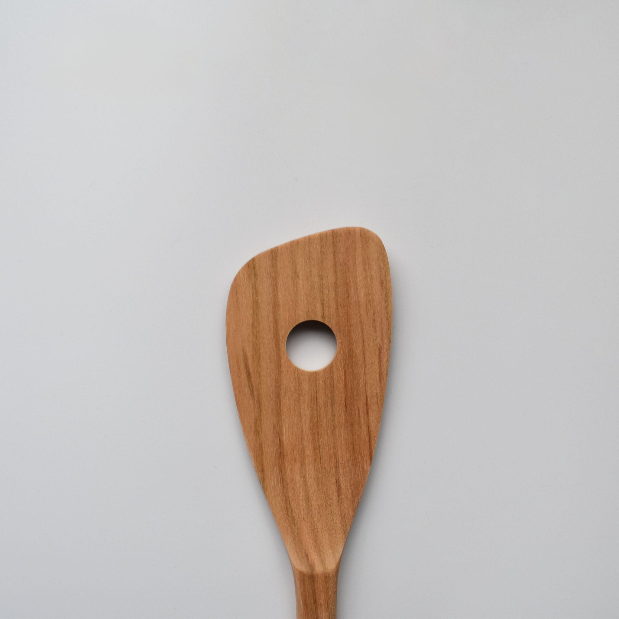 Close-up of the Sakura wood slotted spatula showing the round slot and natural wood grain