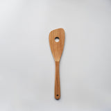 Sakura wood slotted spatula with hanging hole and natural wood grain on a white background