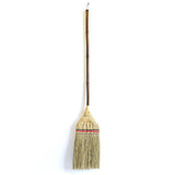 Full view of the Shirokiya Denbei Edo Broom with a premium long handle, featuring intricate straw weaving, red and black decorative bands, and a dark natural bamboo shaft, photographed against a clean white background.