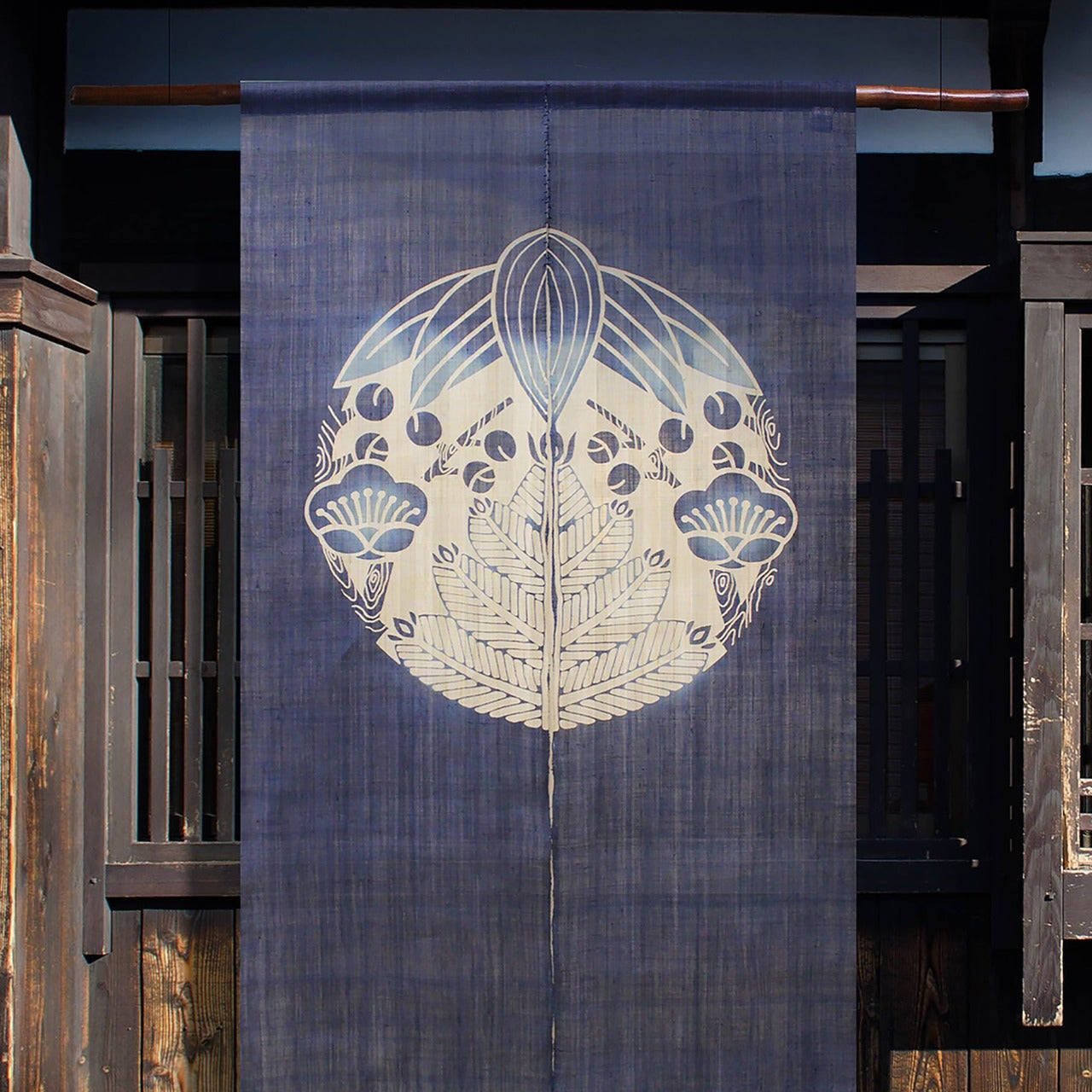 Shochikubai noren curtain in indigo with pine, bamboo, and plum motif hanging in a traditional Japanese doorway.