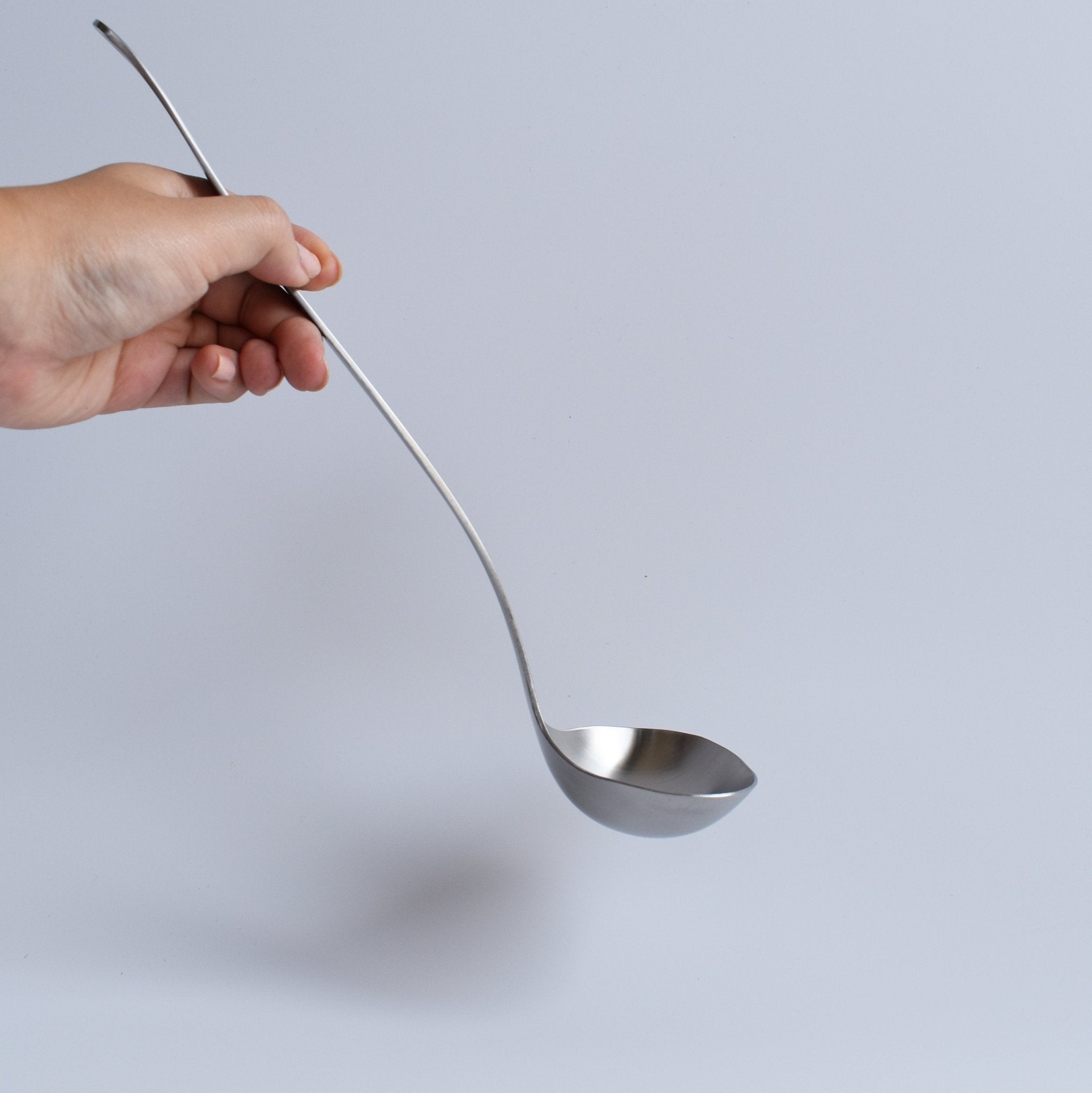 Holding the Sori Yanagi Stainless Steel Ladle — ergonomic Japanese kitchen ladle for soups and stews.