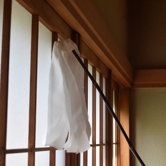 Traditional Japanese silk duster with white silk strips cleaning a wooden shoji screen.