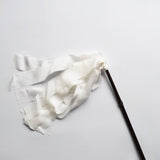 Japanese silk duster with flowing white silk strips and a dark bamboo handle, laid on a white background.
