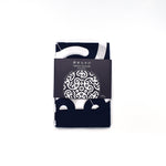 Folded Tokolo Musubi furoshiki cloth with indigo and white geometric wave pattern, wrapped in a minimalist black paper band with Japanese text and design preview.