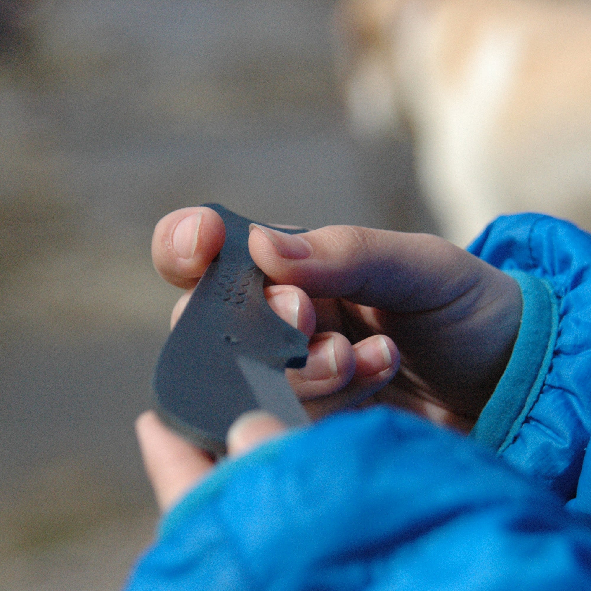 Close-up of a hand holding the Tosa Sperm Whale Knife, showcasing the unique whale-shaped design and matte black finish