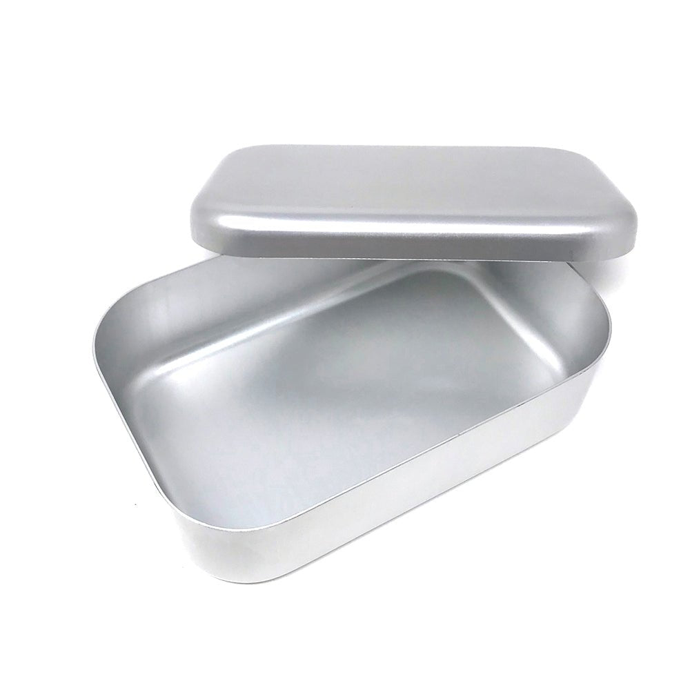 Open silver aluminum bento box with lid propped, showing its smooth, seamless interior and rounded corners in a minimalist Japanese style.