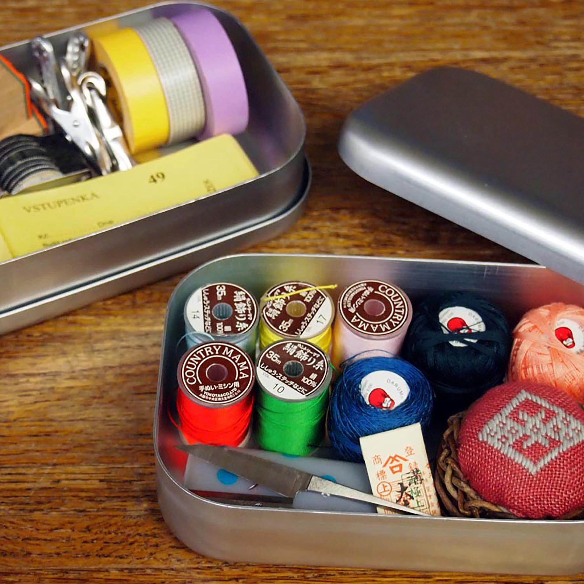 Two open silver aluminum boxes used as storage for sewing supplies and stationery, showcasing their versatility beyond lunch use.
