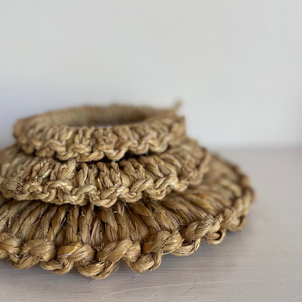 Close-up of three stacked handwoven Japanese straw pot mats showing detailed braided edges and natural fiber texture