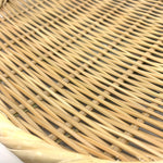 Extreme close-up of the woven bamboo surface and twisted rim of a round Japanese zaru colander on a white background