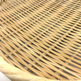 Extreme close-up of the woven bamboo surface and twisted rim of a round Japanese zaru colander on a white background