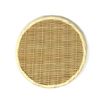 Flat lay of a round handwoven bamboo zaru colander with braided rim, photographed on a white background