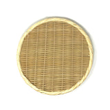 Flat lay of a round handwoven bamboo zaru colander with braided rim, photographed on a white background