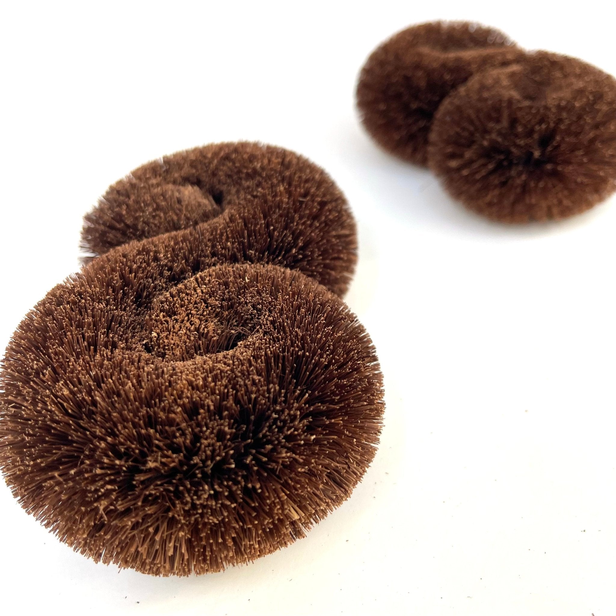 Close-up angled view of traditional Japanese tawashi scrubbers made from tightly bound palm fibers, displayed in pairs on a white background.