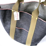 Close-up of Japanese selvage denim tote bag with olive green webbing handles, red stitching, exterior pocket, and Thread Line Tokyo label.