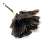 Close-up of a Japanese feather duster made with dark ostrich feathers and a bamboo handle, lying on a white surface