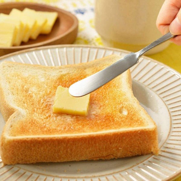 A slice of butter from the Japanese slicer being spread onto toasted bread with a butter knife—perfectly portioned for a cozy breakfast moment.