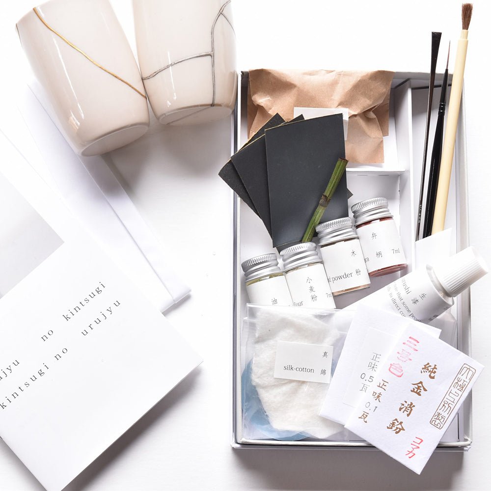 Complete Japanese Kintsugi Kit with gold and silver repair powders, urushi lacquer, tools, and sample repaired ceramics—ideal for traditional pottery mending.