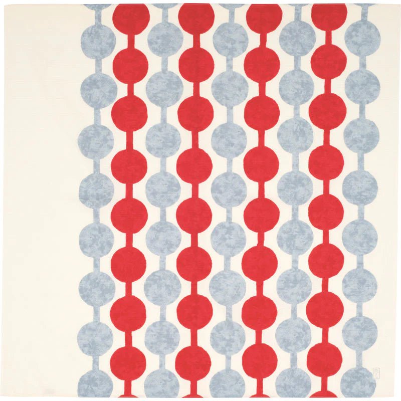 Flat lay of Yumeji Takehisa’s Tsunagi Dango furoshiki cloth featuring repeating red and grey dango pattern on a cream background, traditional Japanese textile design.