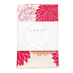 A folded furoshiki cloth from the Hime Musubi series designed by Adeline Klam, featuring a bold pink and red garbera flower pattern. The cloth is neatly packaged with a label written in Japanese and English, showcasing it as an organic cotton furoshiki. The visible floral design includes layered petals in vivid pink, red, and coral on a soft off-white background.