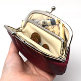 Open Gamaguchi purse in hand, filled with coins and folded bills, highlighting its dual compartments and practical storage capacity.