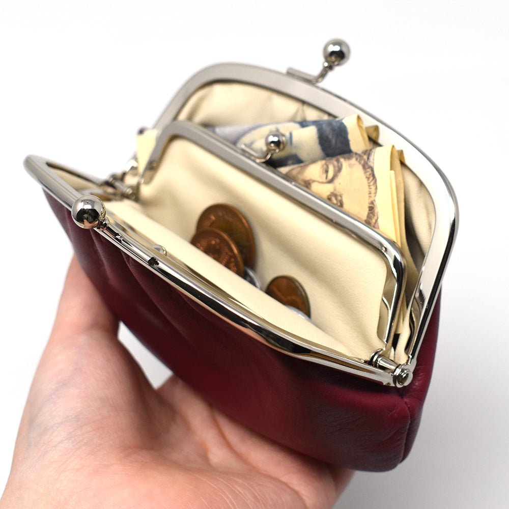 Open Gamaguchi purse in hand, filled with coins and folded bills, highlighting its dual compartments and practical storage capacity.