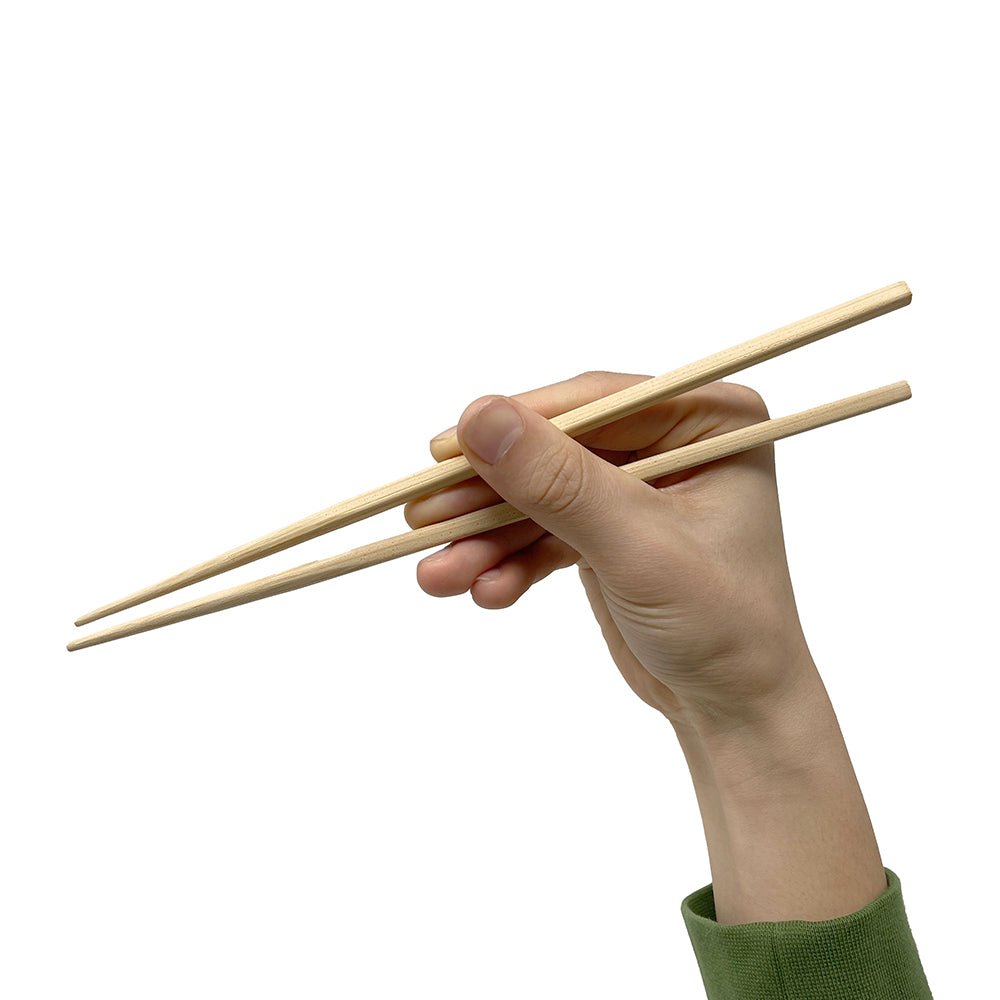 Hand holding natural bamboo chopsticks against a white background. 