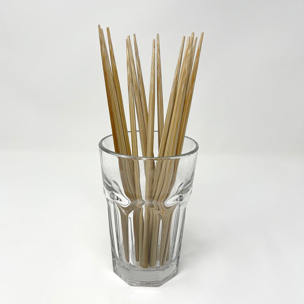 A bundle of natural bamboo chopsticks neatly displayed in a clear glass cup on a white background, showcasing their polished square design and eco-friendly appeal — ideal for minimalist kitchens and traditional Japanese table settings. 