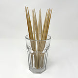 A bundle of natural bamboo chopsticks neatly displayed in a clear glass cup on a white background, showcasing their polished square design and eco-friendly appeal — ideal for minimalist kitchens and traditional Japanese table settings. 