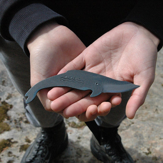 Person holding a Mink Whale Kujira knife in both hands, showcasing the compact size and elegant silhouette of the handcrafted Japanese carbon steel blade