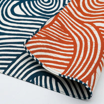 Close-up of reversible Japanese furoshiki cloth featuring bold wavy line patterns in indigo blue and persimmon orange on white cotton fabric.