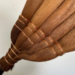 Close-up view of a Japanese shuro angle broom showing the fine handwoven fibers and detailed copper wire binding for durability and craftsmanship.