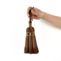 medium Japanese hand broom made from natural palm fibers, held by hand with copper wire detailing for precision cleaning.