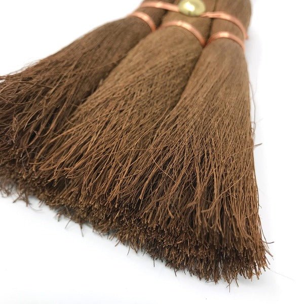 Close-up view of the finely textured palm fiber bristles of a small shuro whisk broom, highlighting the craftsmanship and tight copper wire binding.